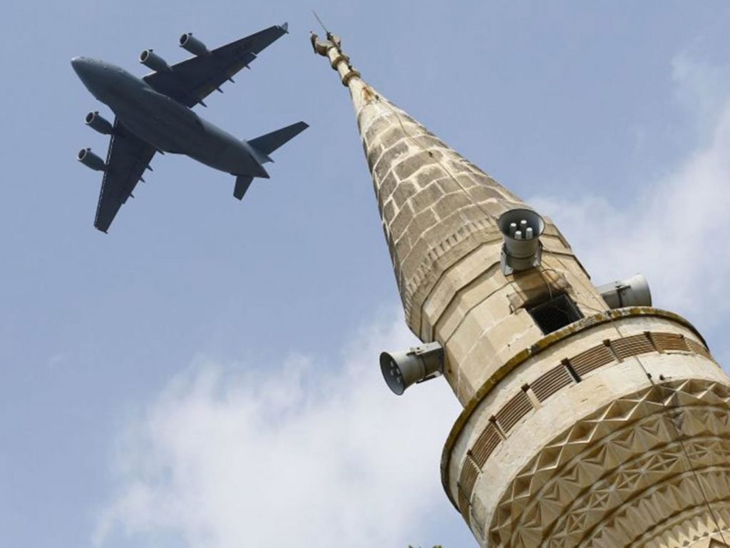 A US Air Force Boeing C-17A Globemaster III large transport aircraft flies over a minaret after taking off from Incirlik air base in Adana, Turkey, on 12 August 2015 Reuters